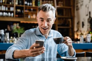 self employed man using smartphone reading news e banking loan lottery winner in cafe