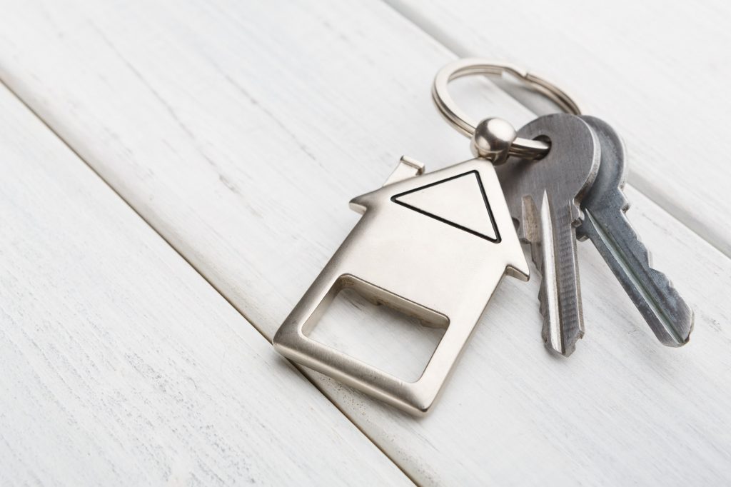 Bunch of keys with house shaped keychain on white wood